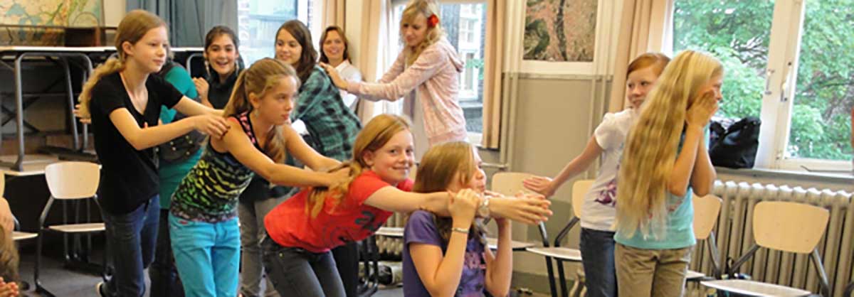 Groep leerlingen voeren samen een theatrale oefening uit tijdens workshop op school