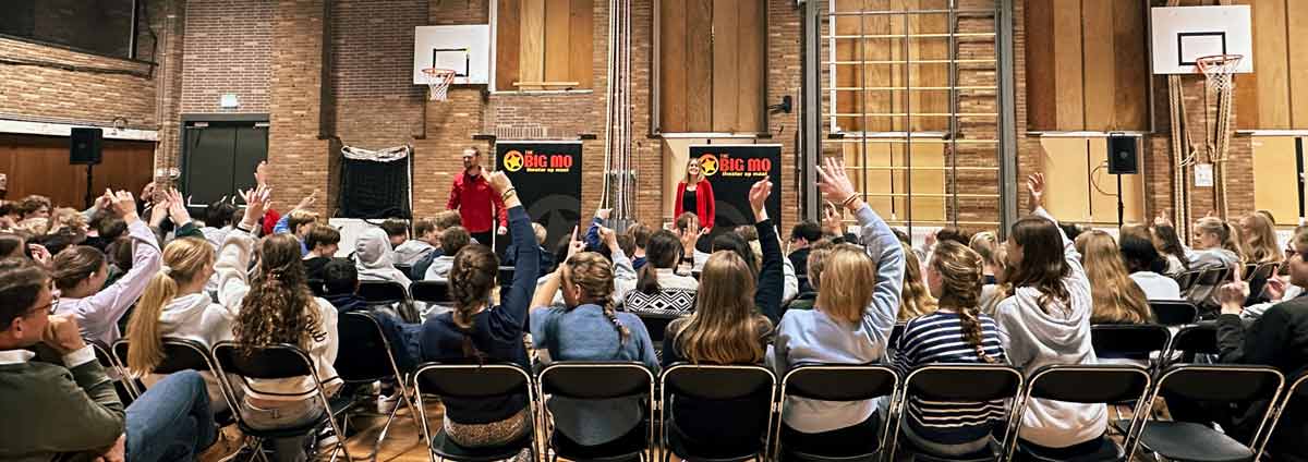 Leerlingen kijken en doen mee met de interactieve voorstelling Hard op de Tong in de gymzaal