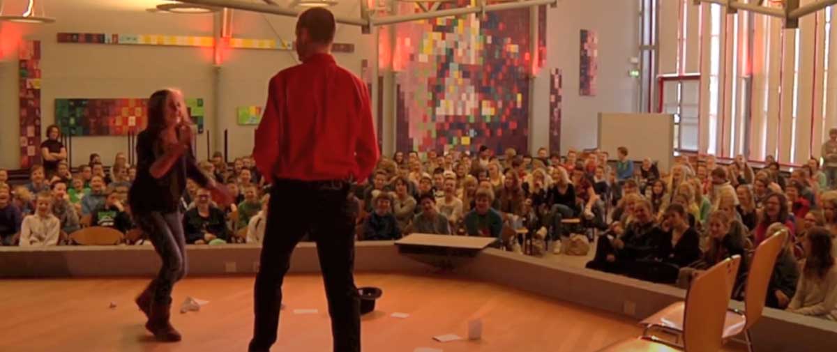 Leerlingen spelen actief mee in improvisatiescène tijdens The Big Mo Theater Show op school.